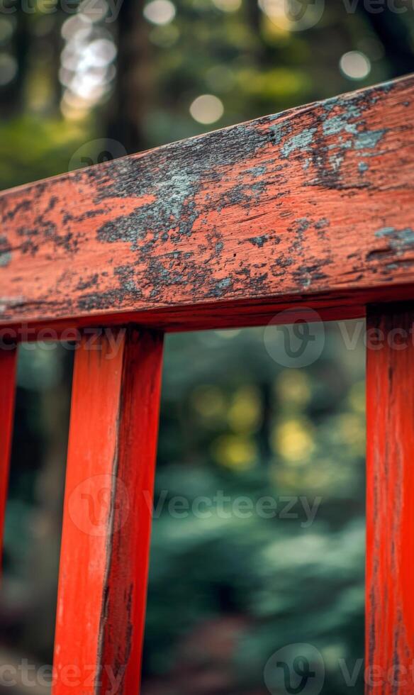 Weathered charm, red painted railing with peeling surface against verdant defocused woodland photo