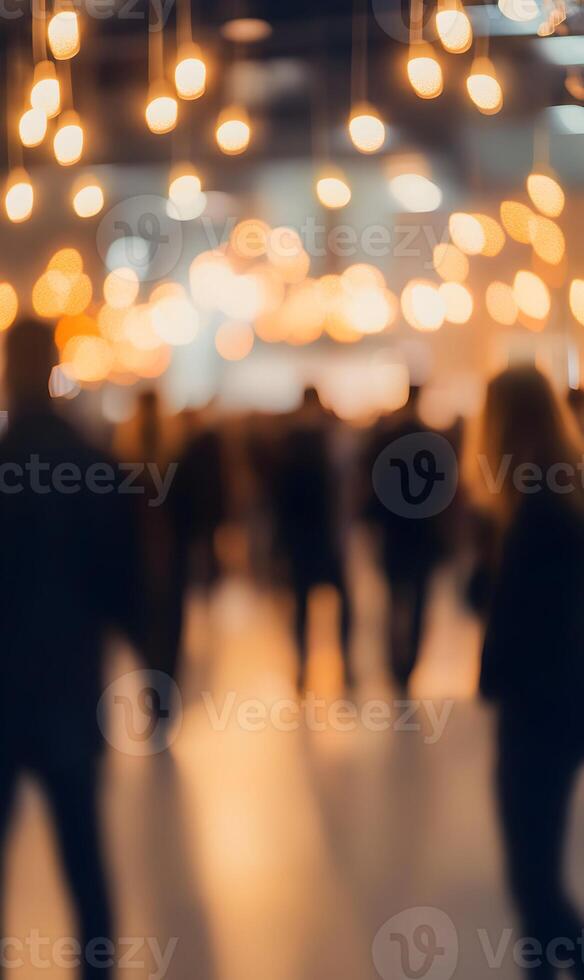 Blurred indoor view of a crowded place with beautiful lights and people walking around photo