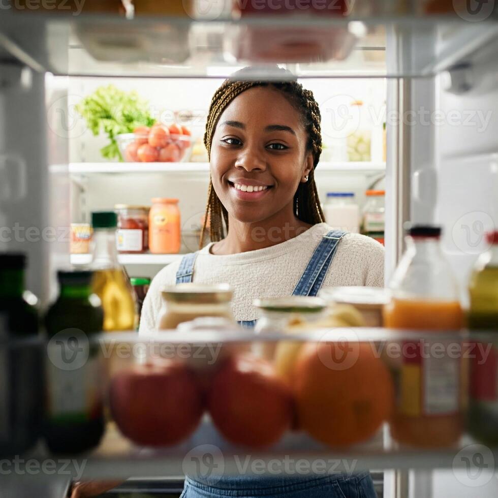 A woman is smiling while looking inside of an open refrigerator photo