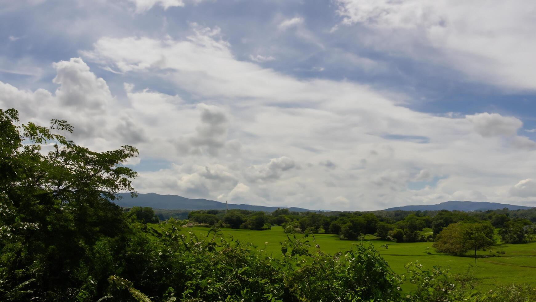Rural landscape, green fields, cloudy sky, mountains, travel photo