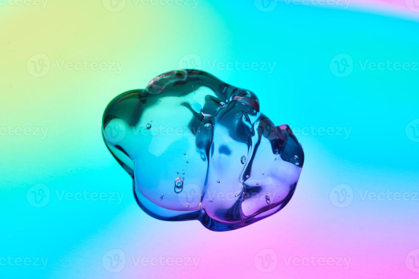 A drop of cosmetic serum on a multicolored background in shades of blue and lilac. photo