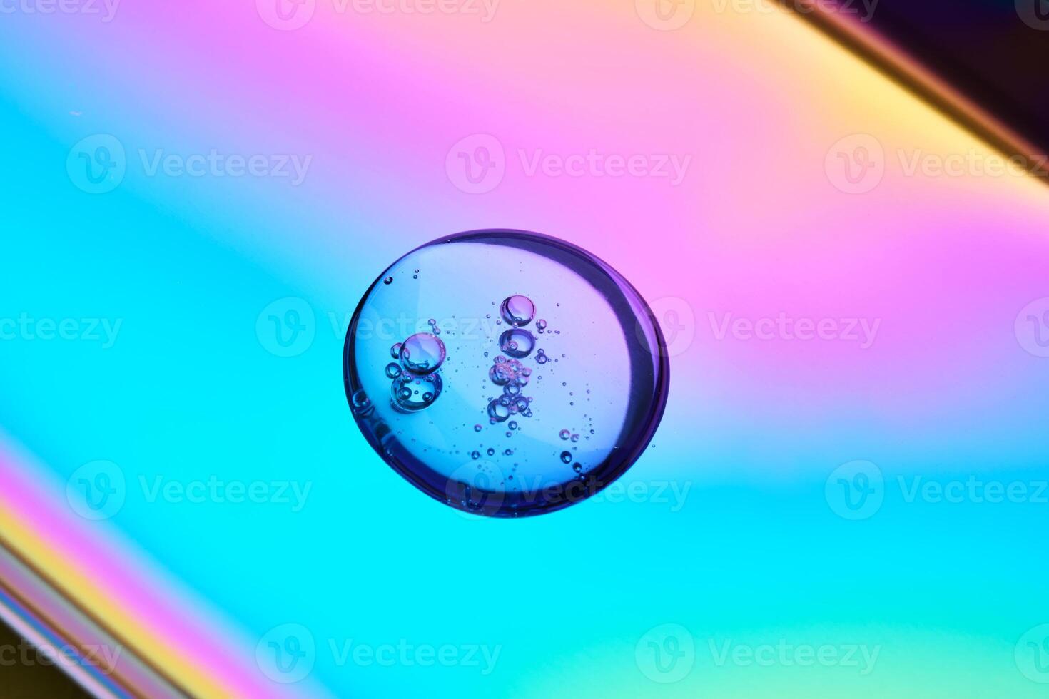 A drop of cosmetic serum on a multicolored background in shades of blue and lilac. photo
