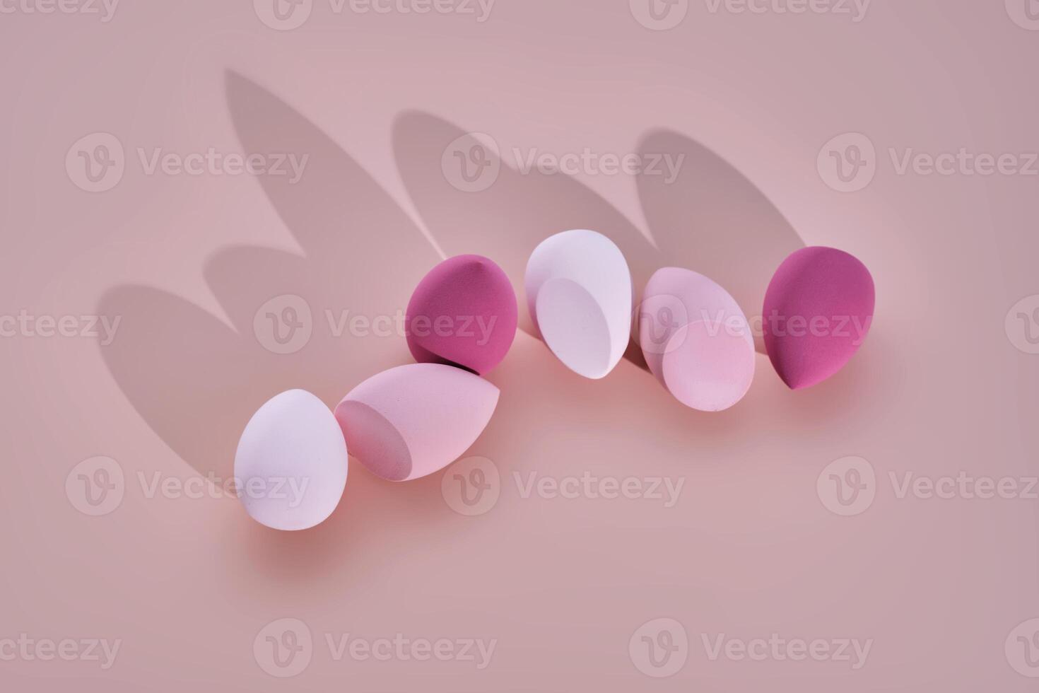 A set of makeup sponges on a pink background. photo