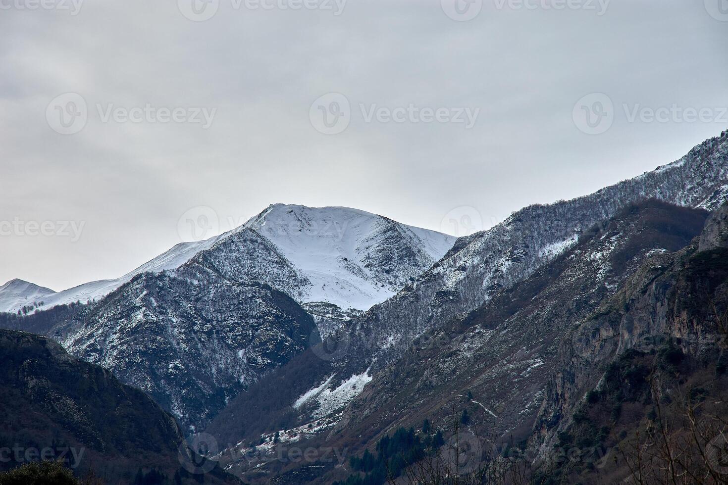 Snow covered Pena de Gata peak surrounded by rugged mountains near Pola de Somiedo photo