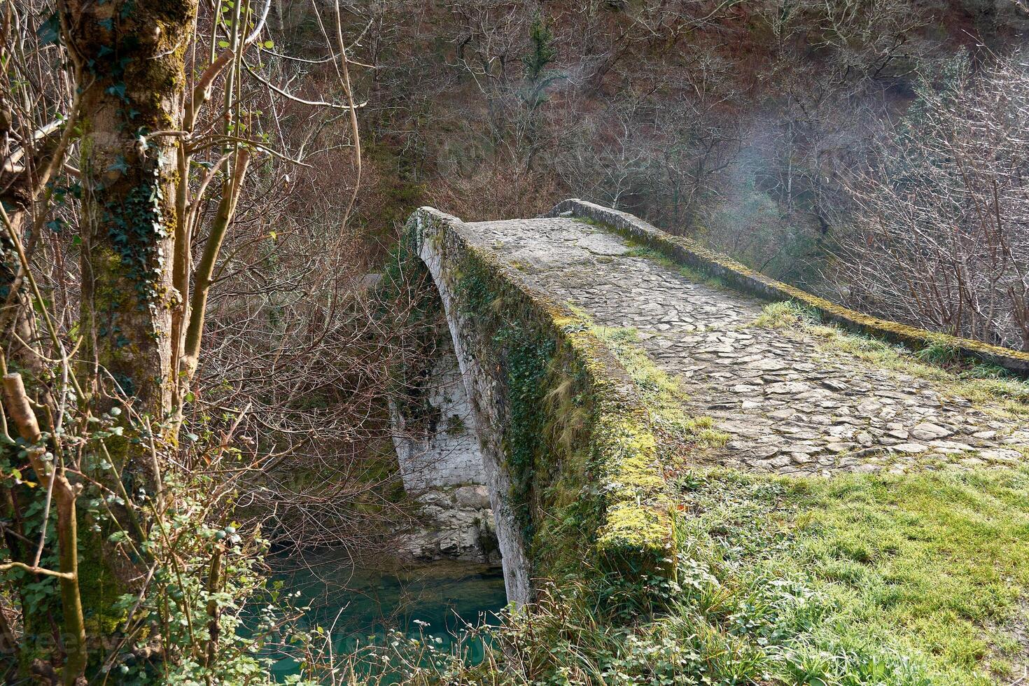 ancient medieval bridge spanning the crystal-clear waters of the dobra river in asturias photo