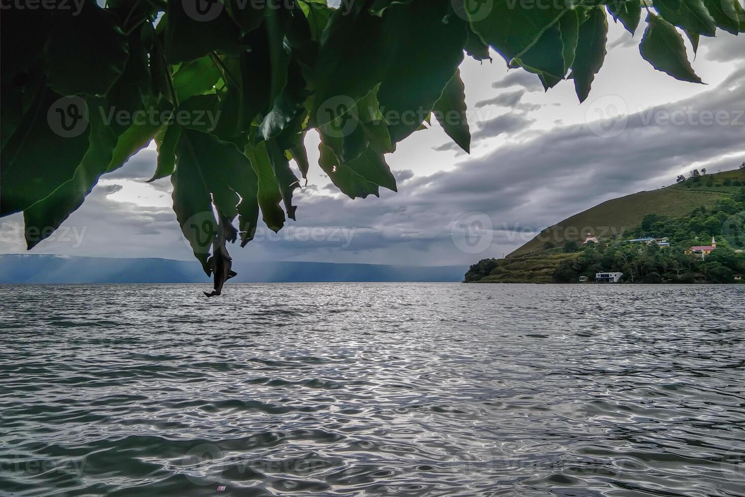 A serene lakeside village nestled amidst lush green hills with stunning views. photo