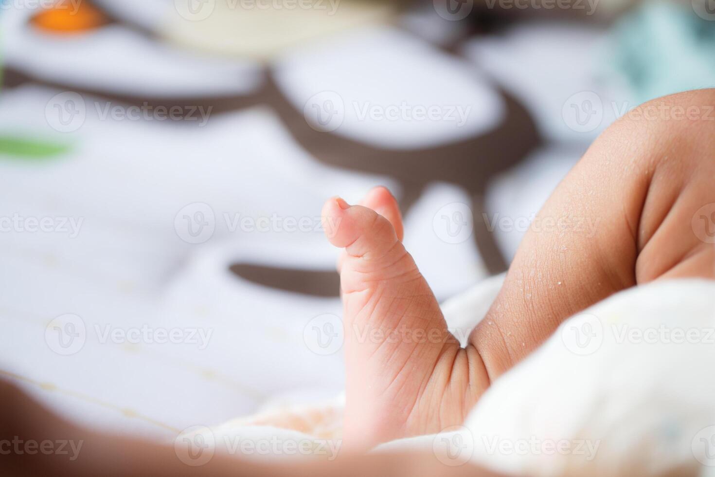 close up of baby foot resting on soft surface, showcasing tiny toes and delicate skin. background features playful design, adding warm and cozy atmosphere photo