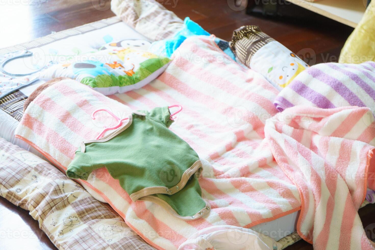 Cozy baby bedding with colorful blankets and clothes on soft surface. scene evokes warmth and comfort, perfect for nursery or play area photo