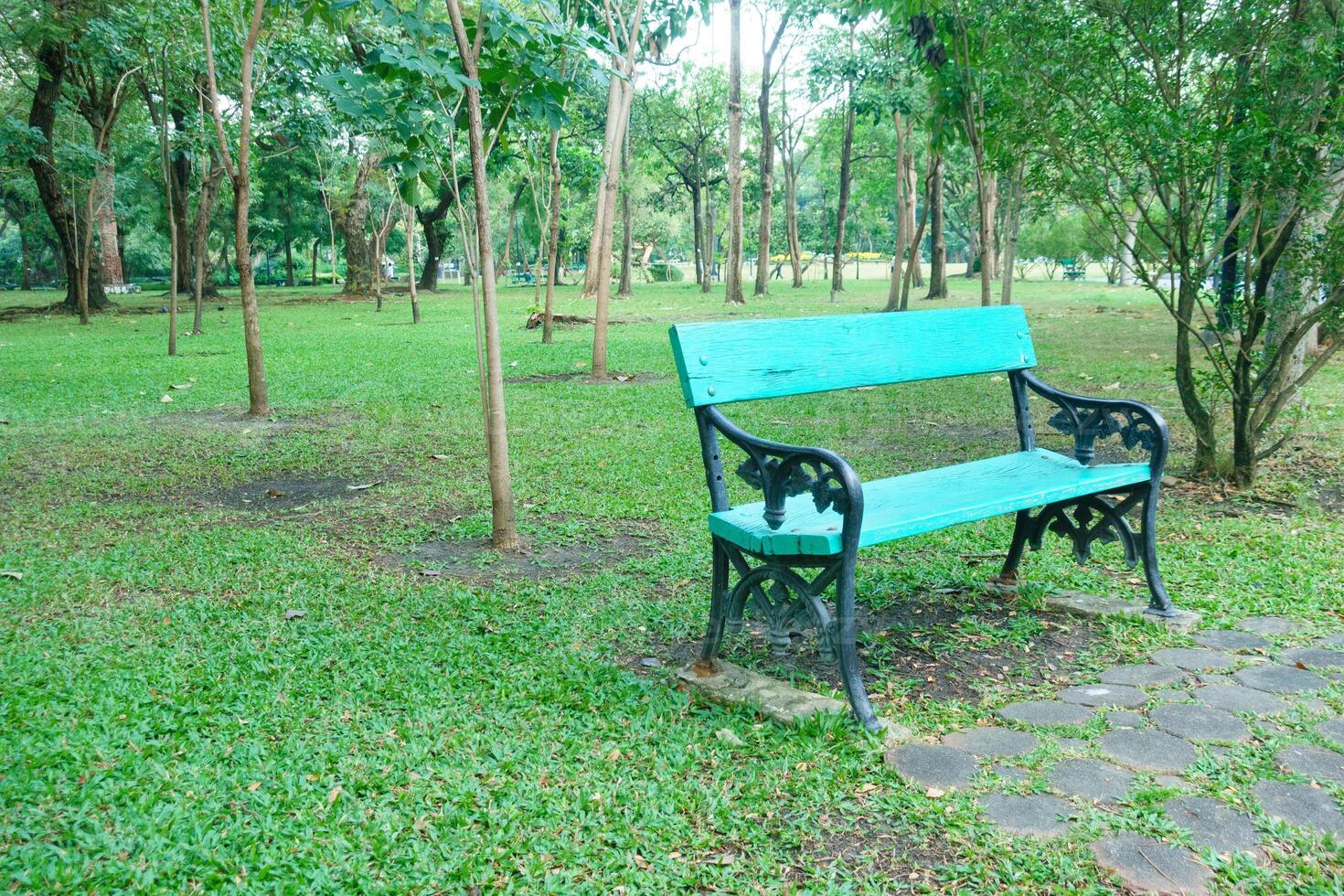 vibrant blue bench sits in lush green park surrounded by trees, inviting relaxation and tranquility. serene atmosphere enhances beauty of nature photo