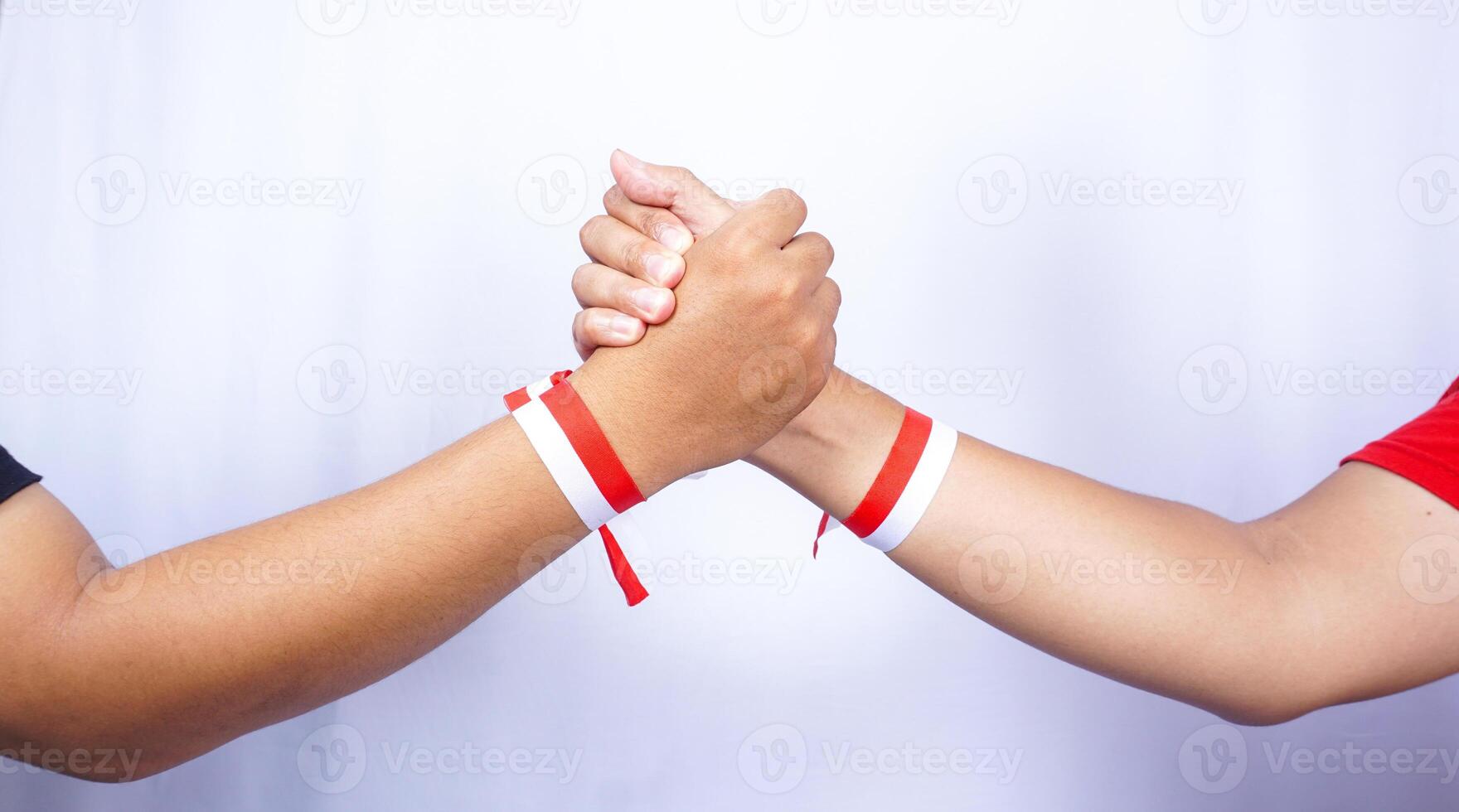 Two Hands with Red and White Ribbons Holding Each Other on White Background photo