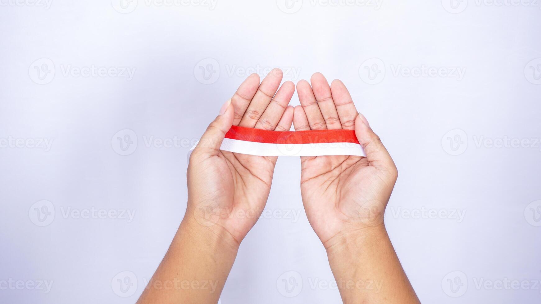 Red and White Ribbons as Representation of Indonesia Flag in Hands on White Background photo