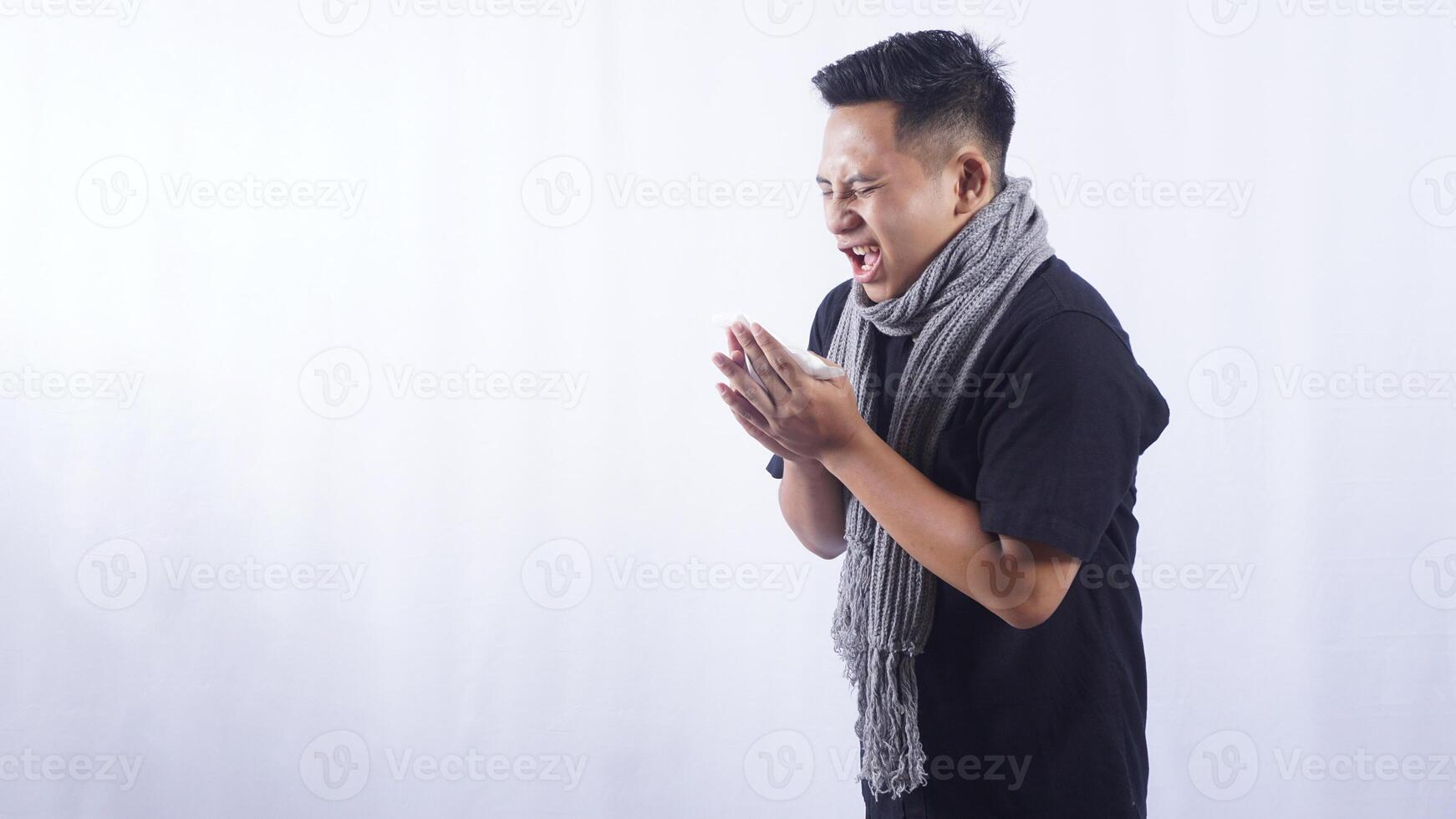 Side View of Sick Asian Man Sneeze Into Tissue Paper on White Background photo