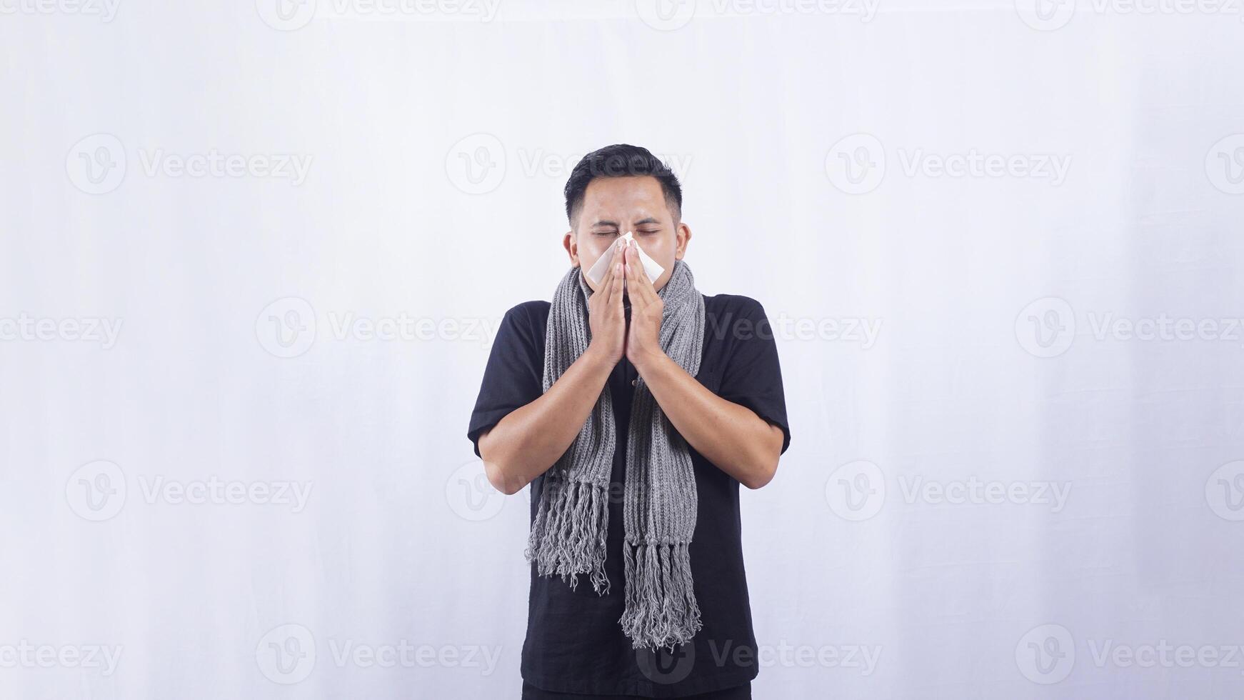 Asian Man Blows His Nose with Tissue Paper Suffering from Flu and Cold on White Background photo