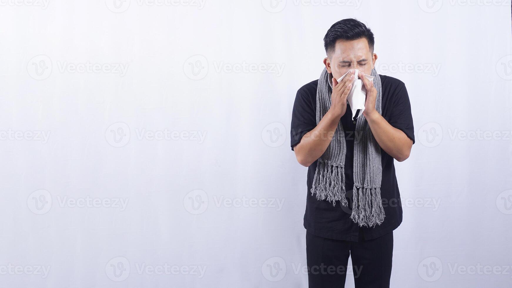 Asian Man Blows His Nose with Tissue Paper Suffering from Flu on White Background photo