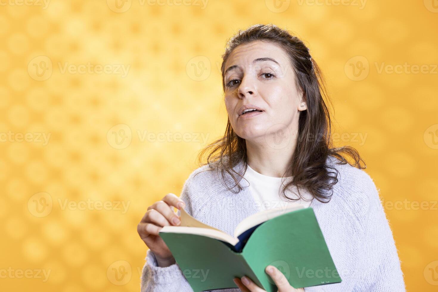 Portrait of woman turning page on book, enjoying reading hobby for relaxation purposes. Bookaholic person with novel in hands enthralled by story, isolated over studio background photo
