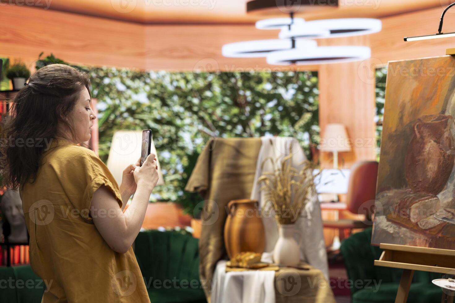 Talented influencer artist using her social media platform to promote her artwork, painter presenting her new masterpiece on online content. Filming a vlog on smartphone for digital marketing. photo
