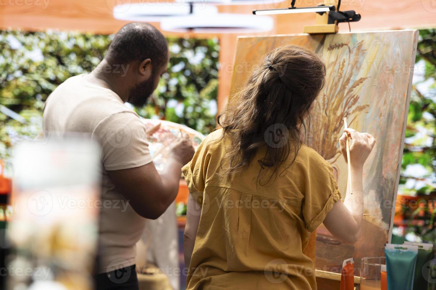Team of painters recording an artistic tutorial for the internet art class, teaching painting techniques and showing demonstration for creativity. Man and woman working on e learning lesson. photo