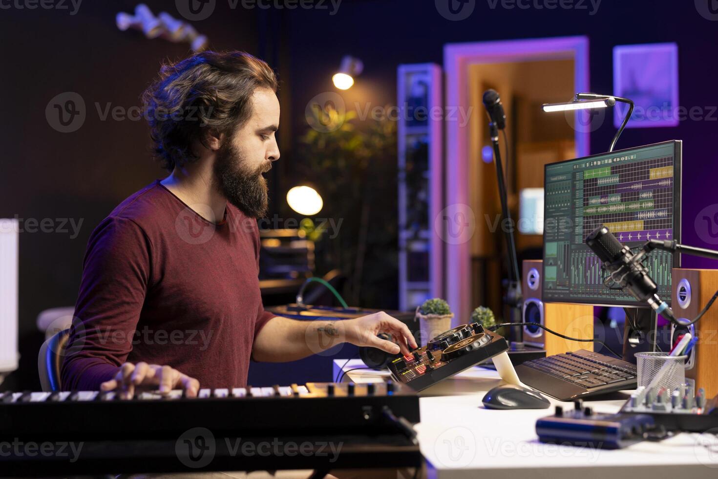Sound engineer mixing and mastering new songs in home studio, adding piano electronic keyboard tunes. Young talented producer composing music with stereo equipment and synthesizer. photo