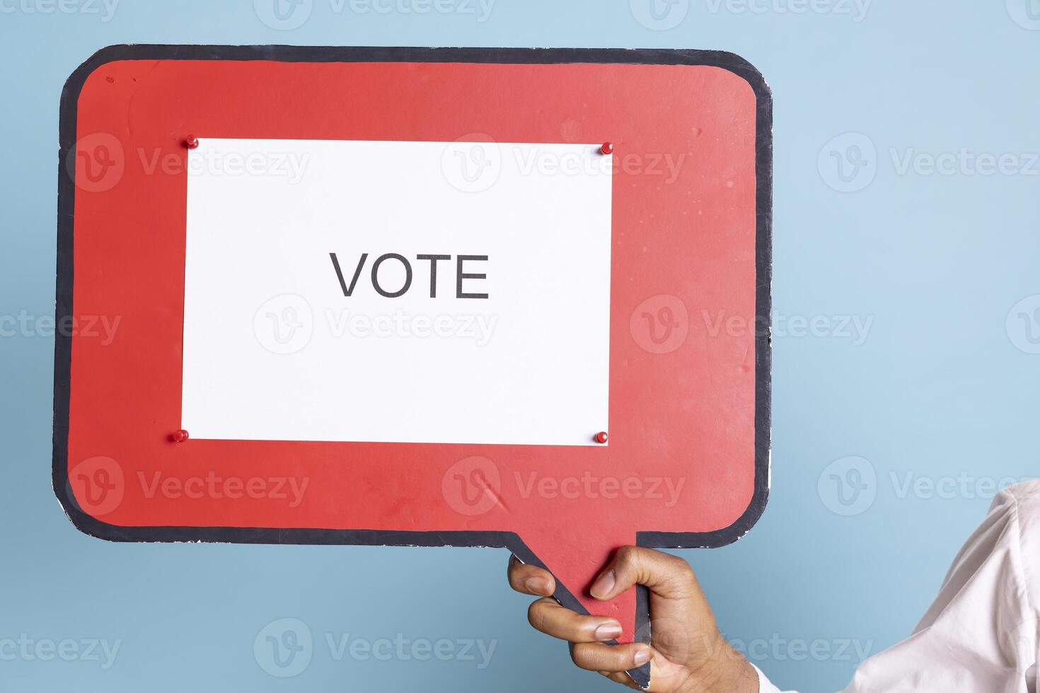 Hotel concierge holding a speech bubble with the message to vote, urging people to get interested in politics on camera. Skilled bellhop with suit and tie showing a marketing ad icon. photo