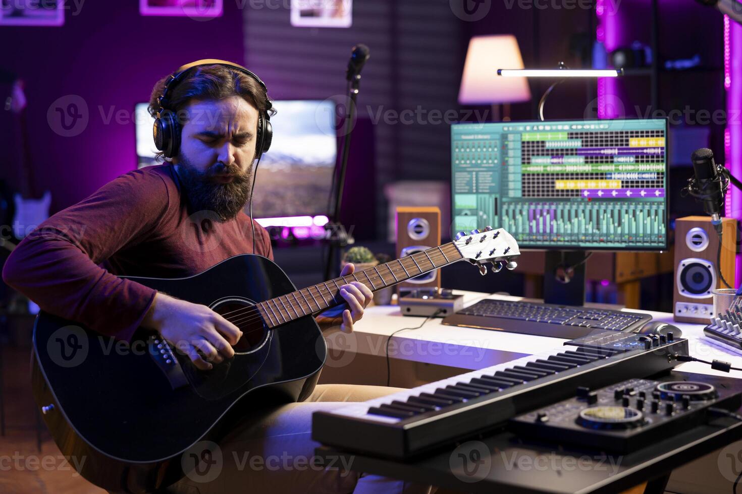 Artist recording his acoustic guitar tunes in home studio, using daw software interface on computer. Composer playing new string accords on musical instrument, acoustical engineering. photo