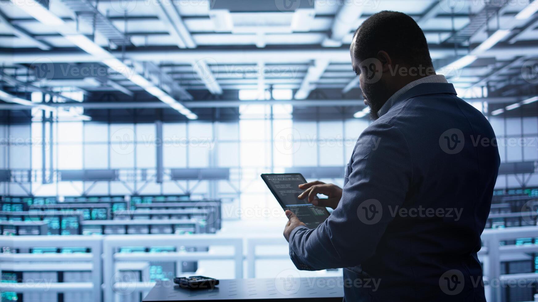 Technician in server hub workplace installing newly ordered storage unit, checking parameters with tablet. IT expert in data center holding device, replacing storage mainframes components, camera B photo