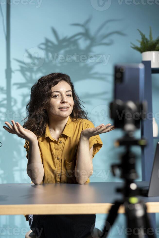 Joyful woman filming vlog with high tech gear in professional studio, speaking into mic equipment. Radiant influencer chatting with subscribers about trending topics on internet channel photo