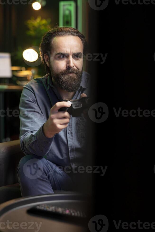 Man playing intense online videogame in neon illuminated living room, spamming buttons on controller. Gamer participating in internet esports competition, playing on gaming console, close up photo