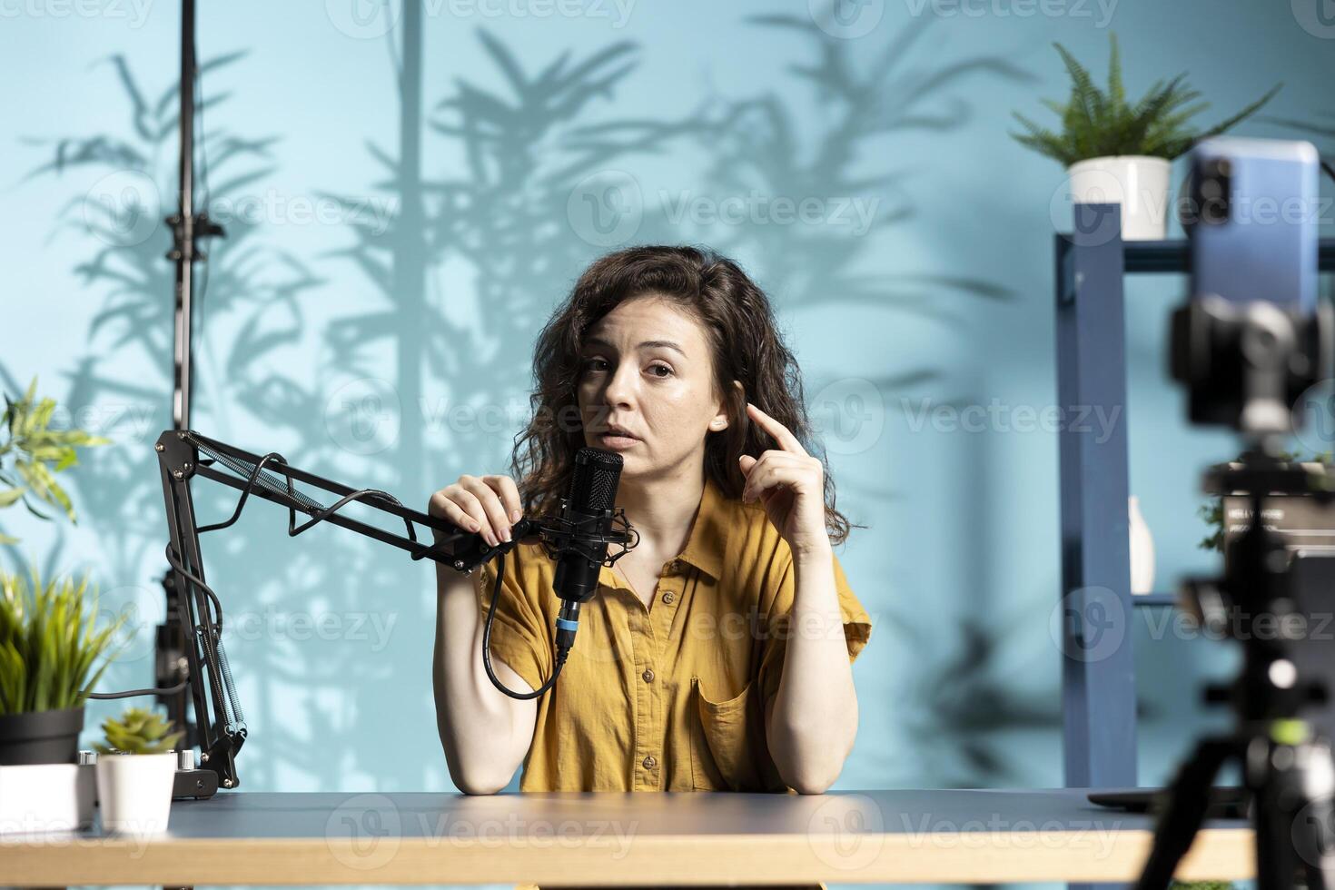 Internet star recording channel intro for digital platforms, talking into high quality microphone, discussing with social media followers. Female influencer setting up equipment for viral photo