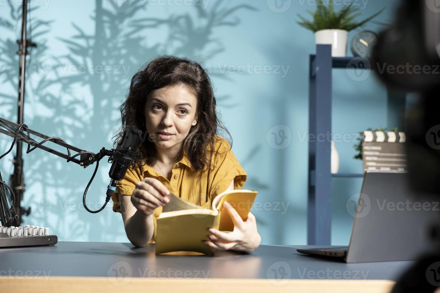 Smiling internet star in studio reviewing newly released hardcover book from publisher. Joyous woman presenting and reading new novel from author for subscribers, promoting book photo