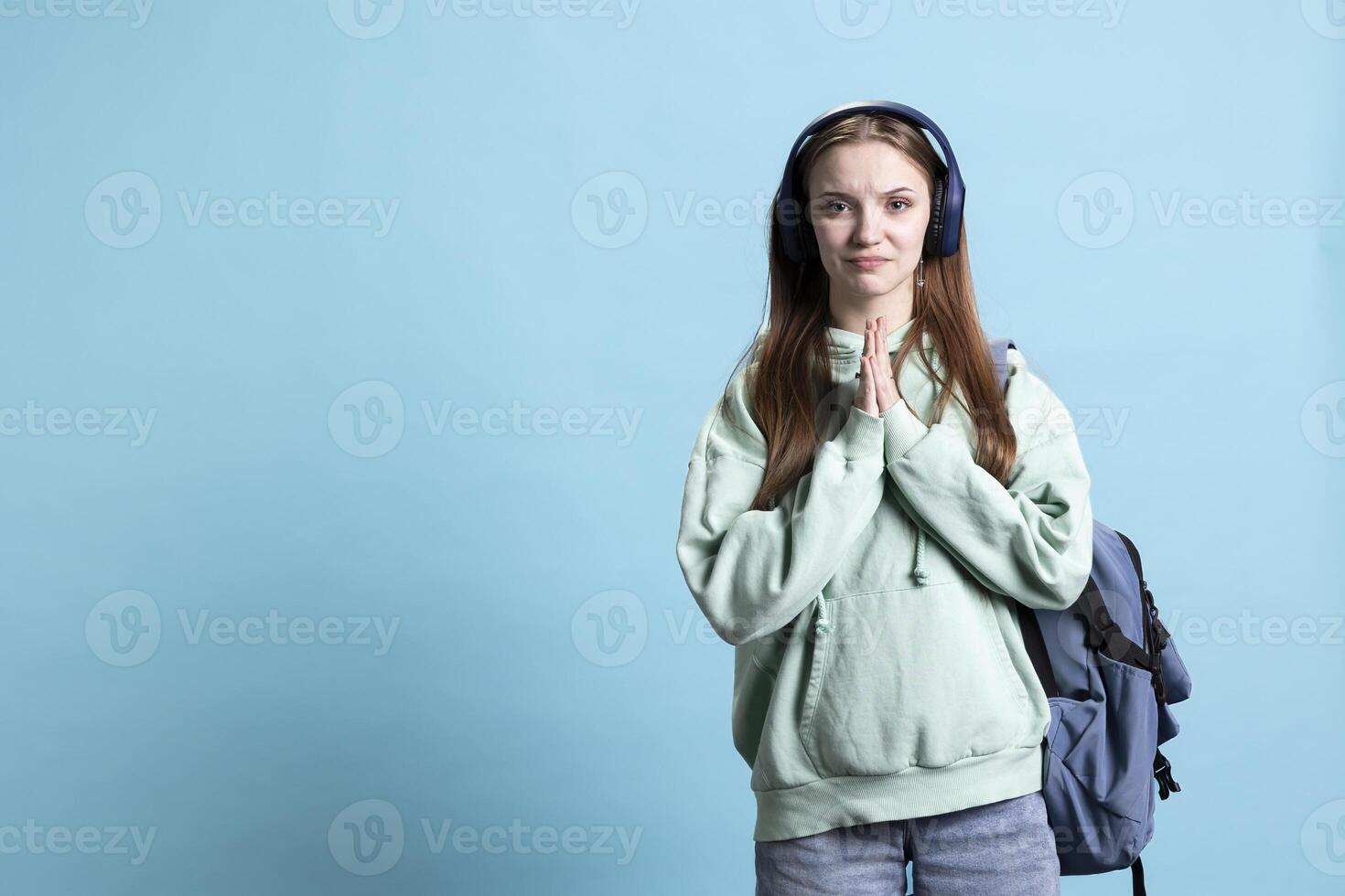 Stressed person doing imploring hand gesture and sulking, being in distress, needing favor, studio backdrop. Desperate young lady soliciting aid, doing please gesturing, requesting assistance photo