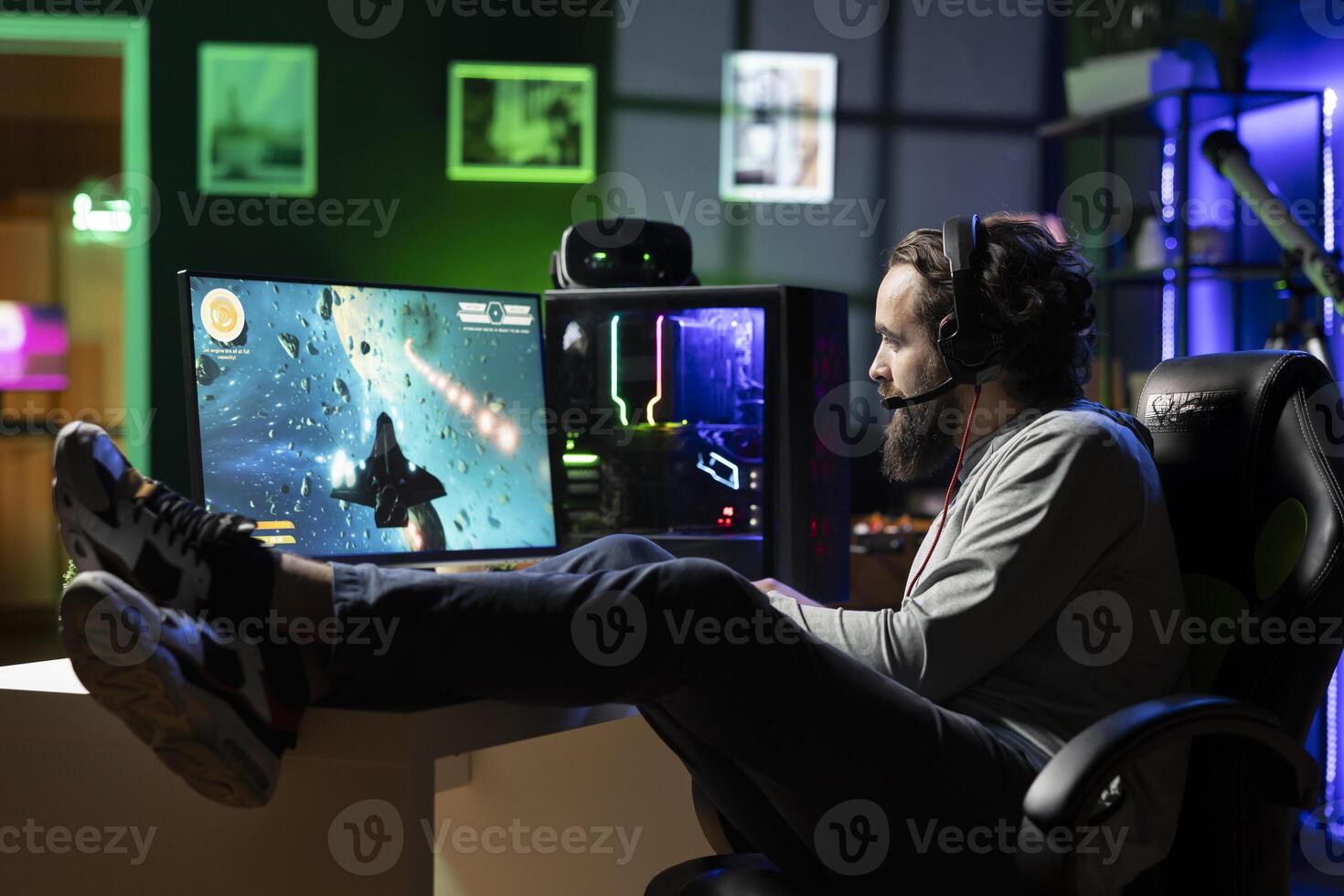 Man talking with friends online while playing videogame with spaceship shooting laser bullets at asteroids, lounging on desk. Gamer chats with teammates while hitting targets in SF game, relaxing photo