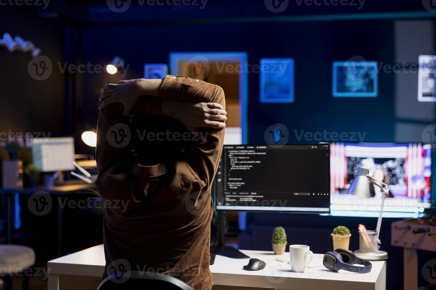 Programmer doing software quality assurance, stretching arms behind back after reading source code, feeling fatigued. IT expert taking break from work to relax muscles after inspecting coding photo