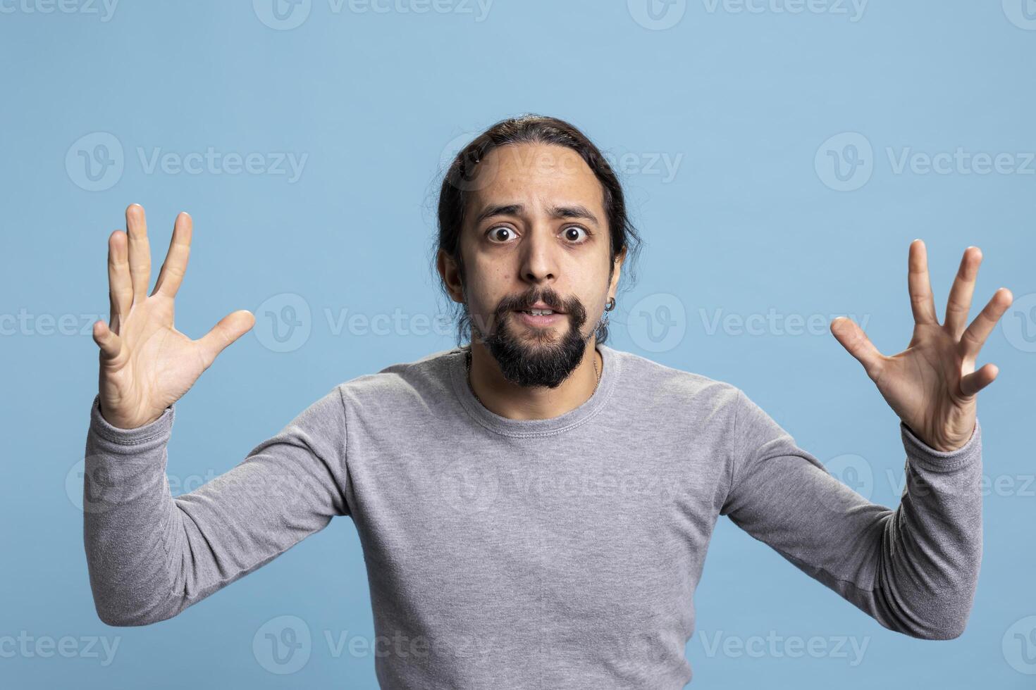 Frustrated angry person expressing his intense emotions and anxiety on camera, showcasing anger management issues and rage. Young adult being furious and irritated with something in studio. photo