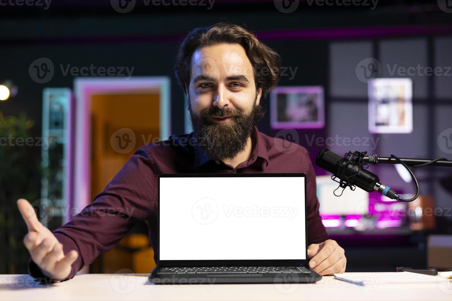 Portrait of cheerful man in studio filming tech tutorial on how to do maintenance on mockup laptop. Happy online show host teaching subscribers how to open and fix busted isolated screen notebook photo