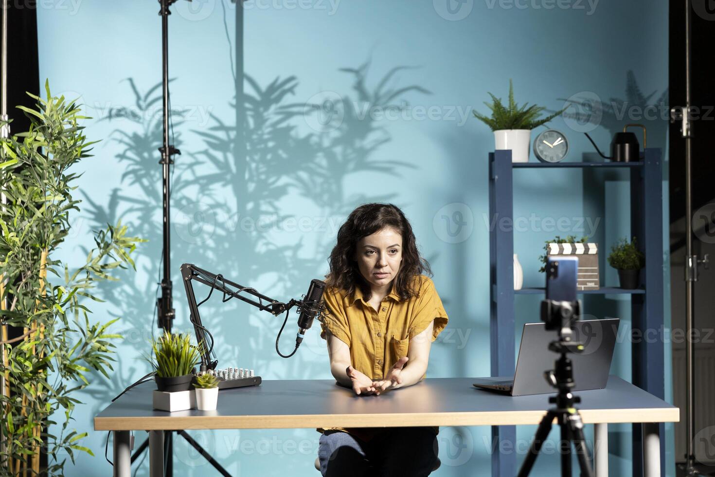 Content creator using mic in studio to do ASMR , discussing with viewers using soothing voice. Woman using professional microphone and smartphone to record podcast with crisp sound photo