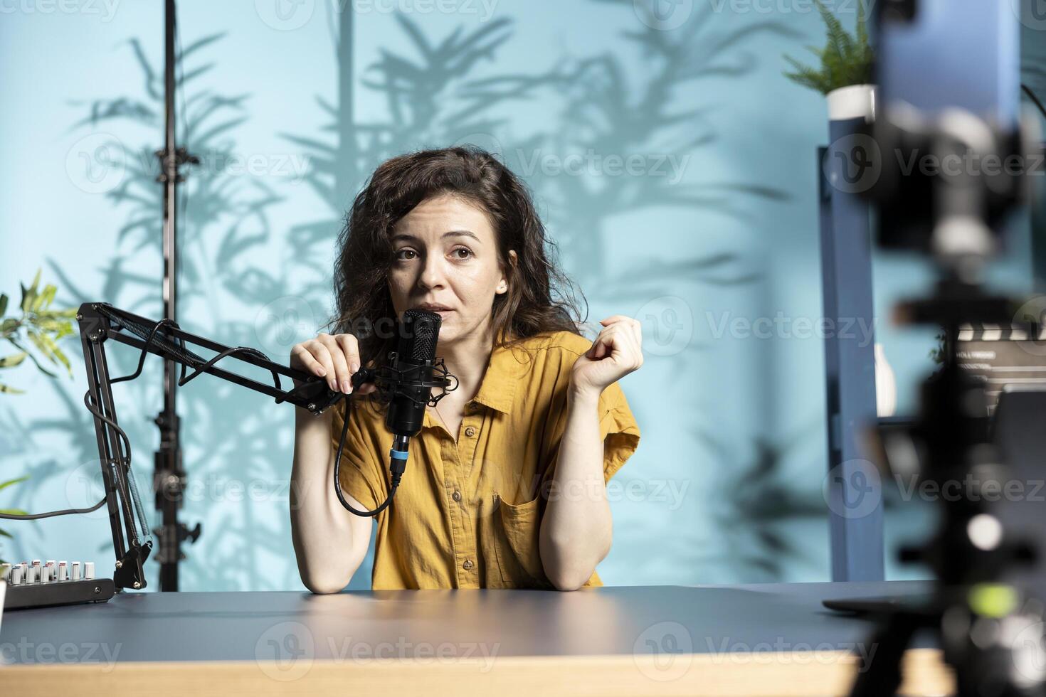 Media star recording channel intro for digital platform, talking into high quality microphone, discussing topics. Content creator setting up mic gear for next segment of viral photo
