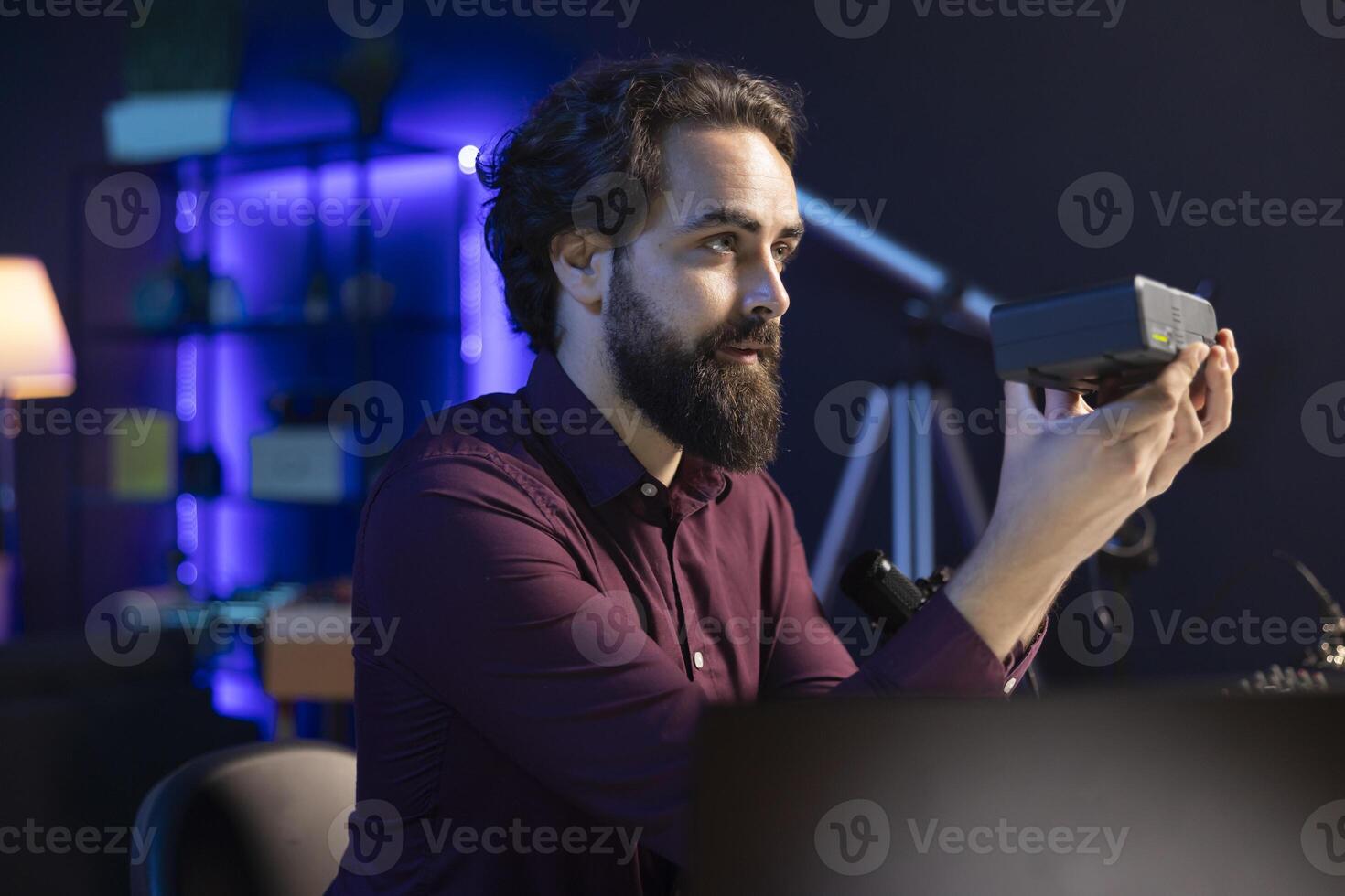 Tech expert paid by sponsor to endorse portable V mount battery, filming commercial in home studio. Content creator contracted by company to promote lithium li-ion charging device to fans photo