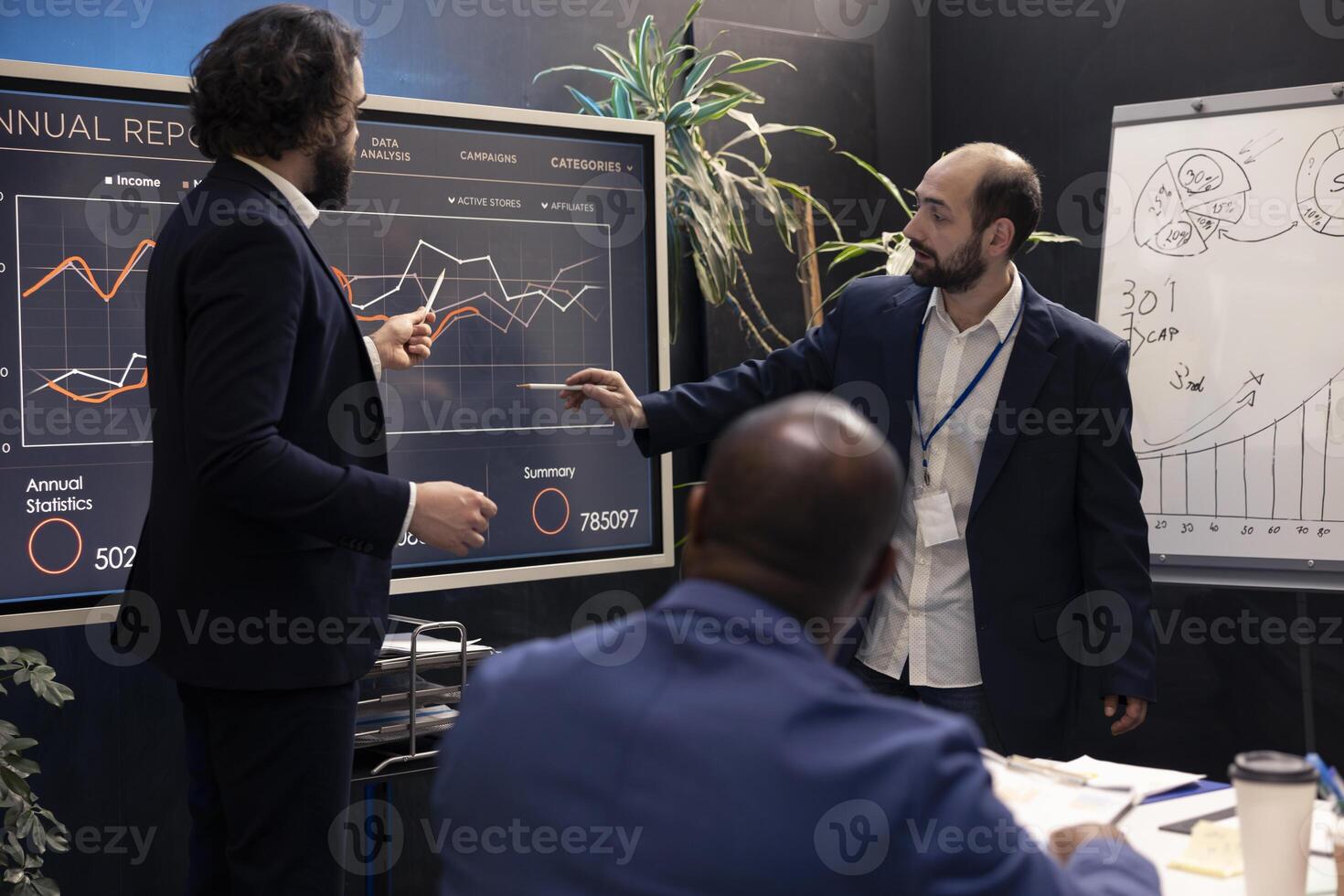 Business partners host a meeting to share insight and ideas about infographics extracted from online research, pointing at interactive board. Team collaborating on development plan. photo