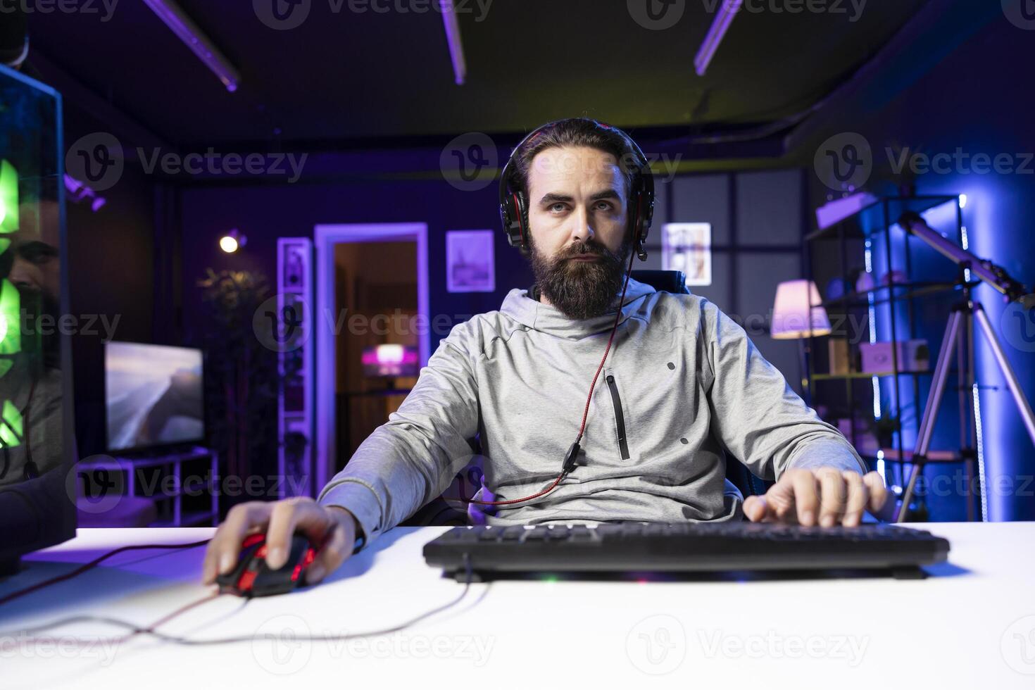 Player upset after losing while playing FPS videogame, using headphones mic to talk with friends. Gamer at computer desk feeling anger after receiving game over screen, blaming online teammates photo