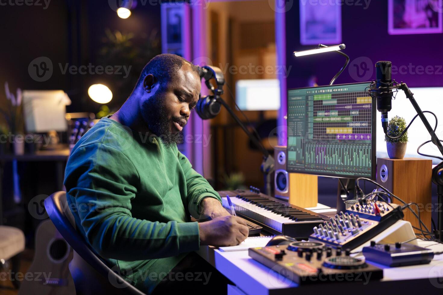 Talented artist composing new lyrics for his tracks and recording music with audio devices in his home studio. Singer composer writes melodic material by taking notes and creating rhymes or songs. photo