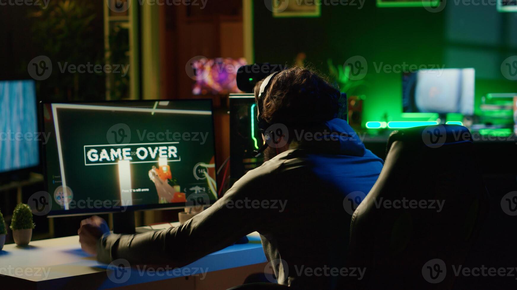 Angry man frustrated after losing science fiction FPS videogame level in RGB lit apartment late at night. Upset gamer raging, punching table after failing in online multiplayer shooter photo