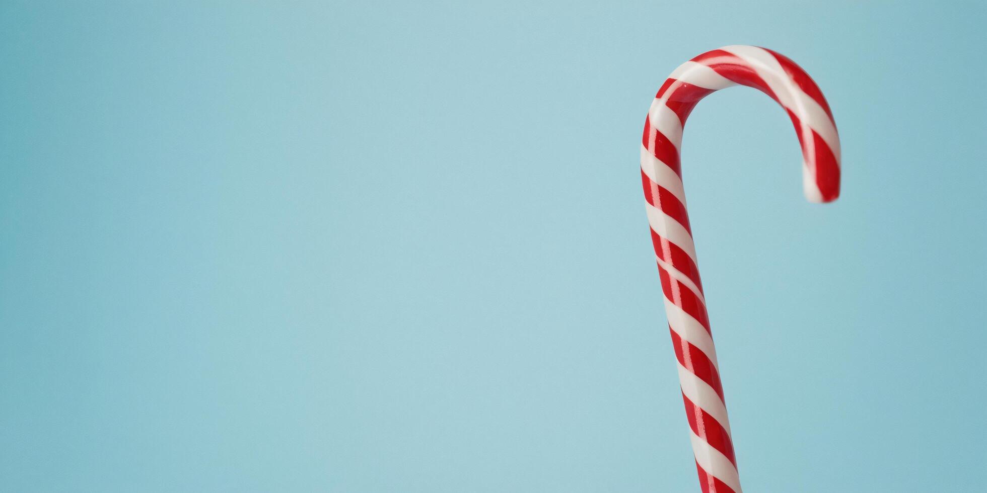 Single red and white candy cane against a light blue background. photo