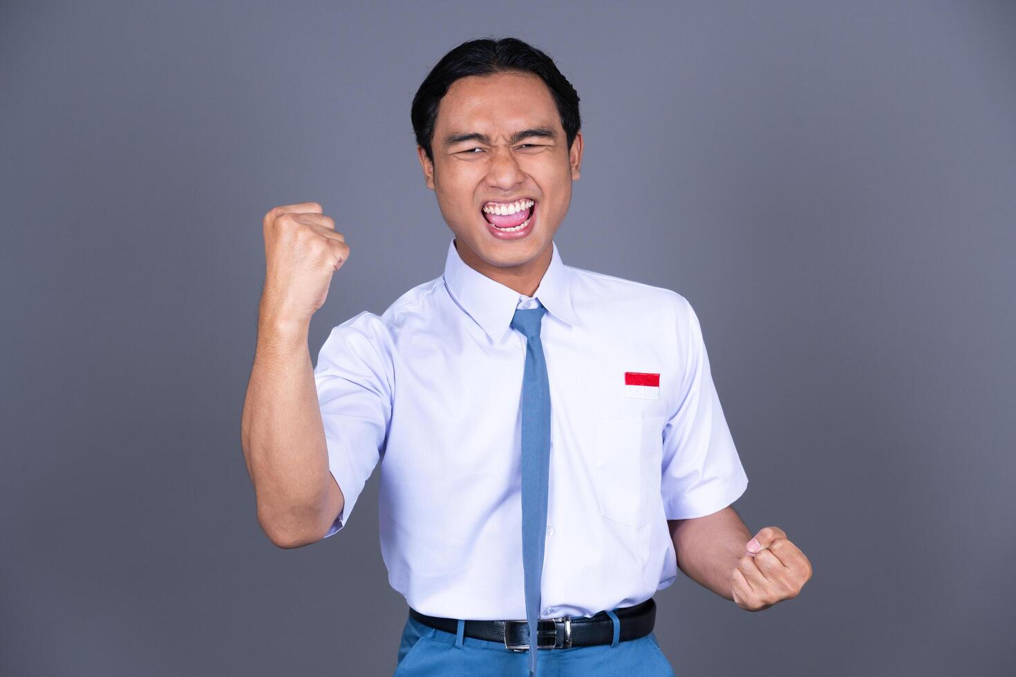 Indonesian Male High School Student in Uniform Gesture Celebrating and Shouting photo