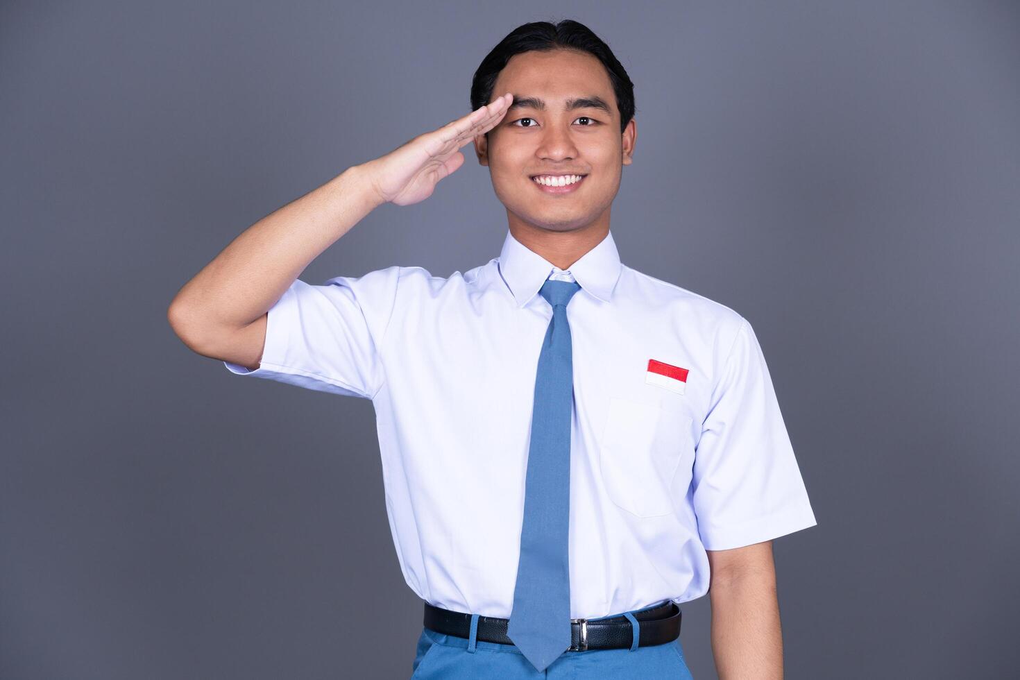 Indonesian Male High School Student in Uniform Hand Salute Gesture And Smiling photo