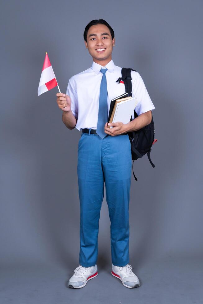 Indonesian Boy High School Student in Uniform Waving Indonesian Flag Background photo