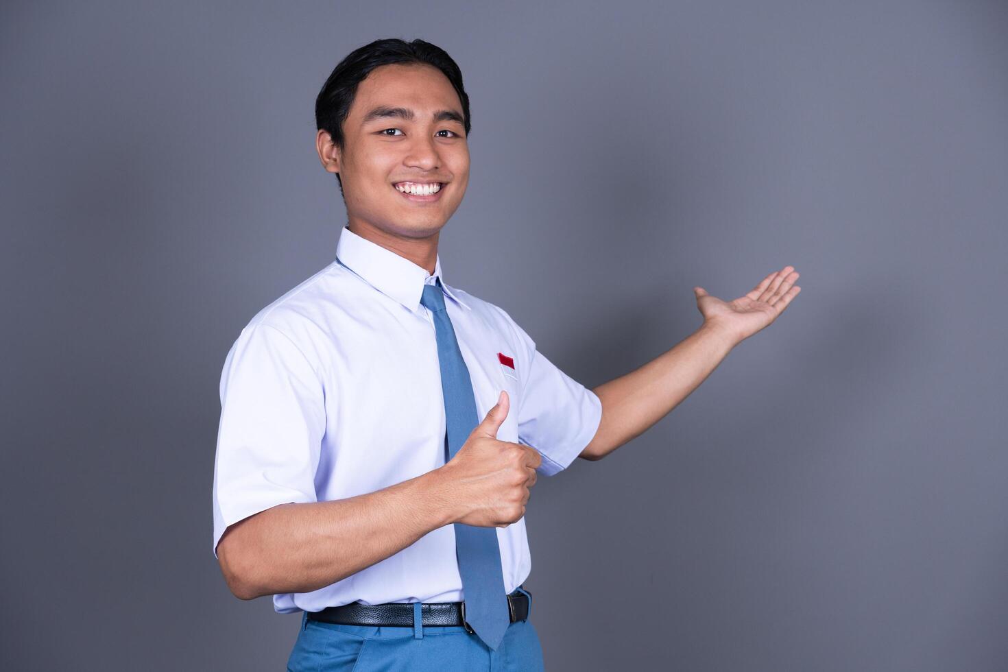 Indonesian Male High School Student in Uniform Presenting Gesture Isolated Background photo
