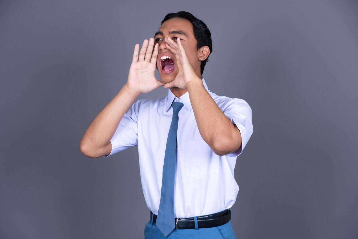 Indonesian Male High School Student in Uniform Shouting with Hand on Mouth photo