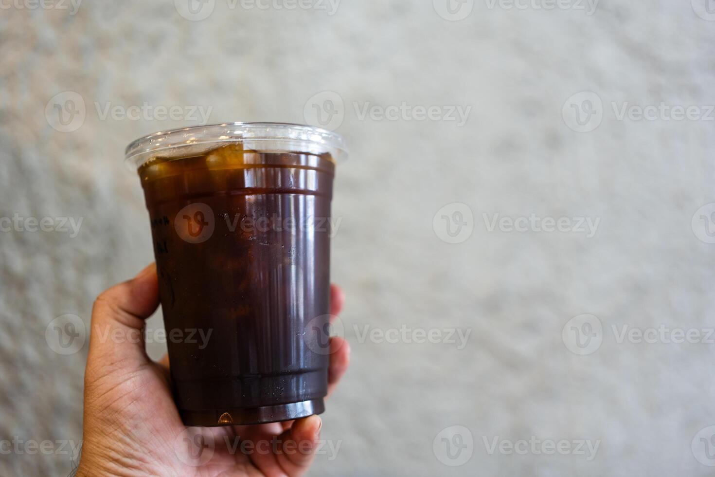 Hand holding iced black coffee photo