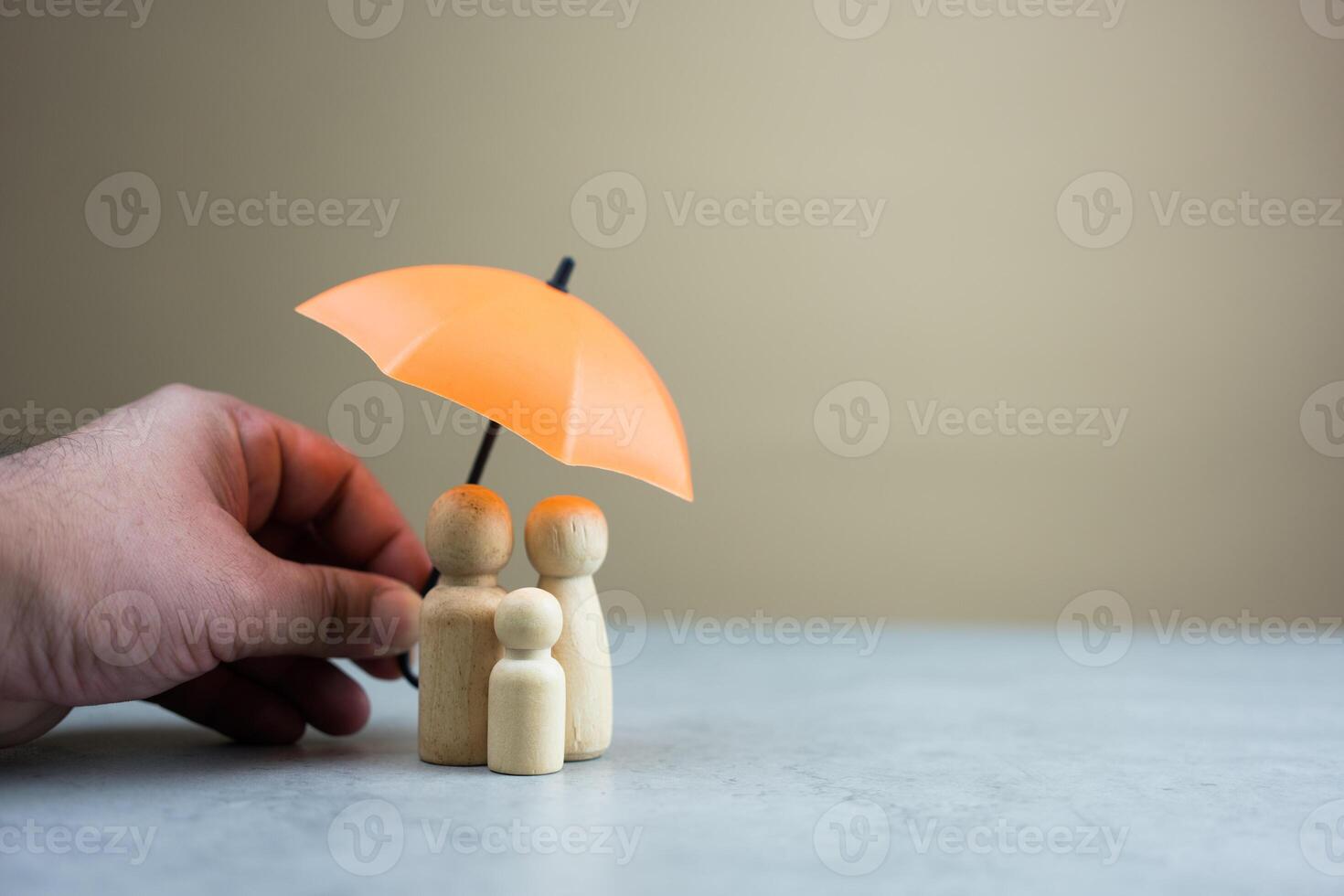Insurance concept. Someone hand holding use orange umbrella protects family. photo