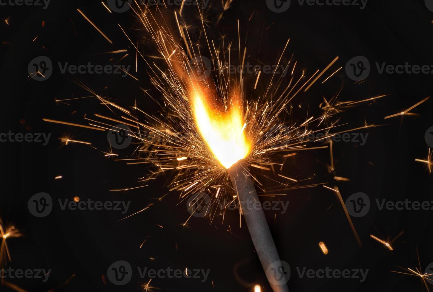 A sparkler is lit with a black background photo